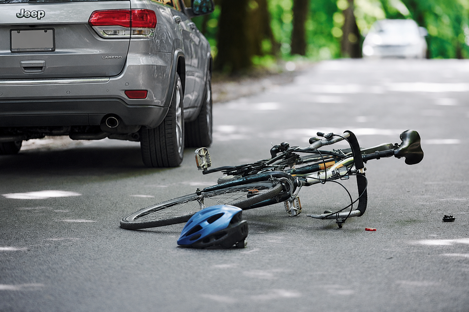 A car hit a bike on a forested road